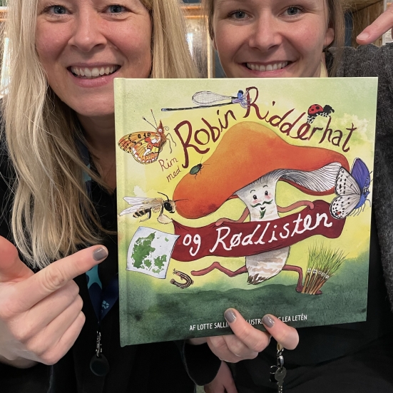 To kvinder holder en billedbog og peger på den