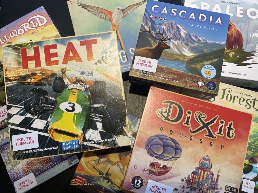 BIllede af forskellige brætspil i en bunke: Heat, Cascadia, Paleo, DiXit, Wingspan og andre man ikke kan læse titlerne på. 